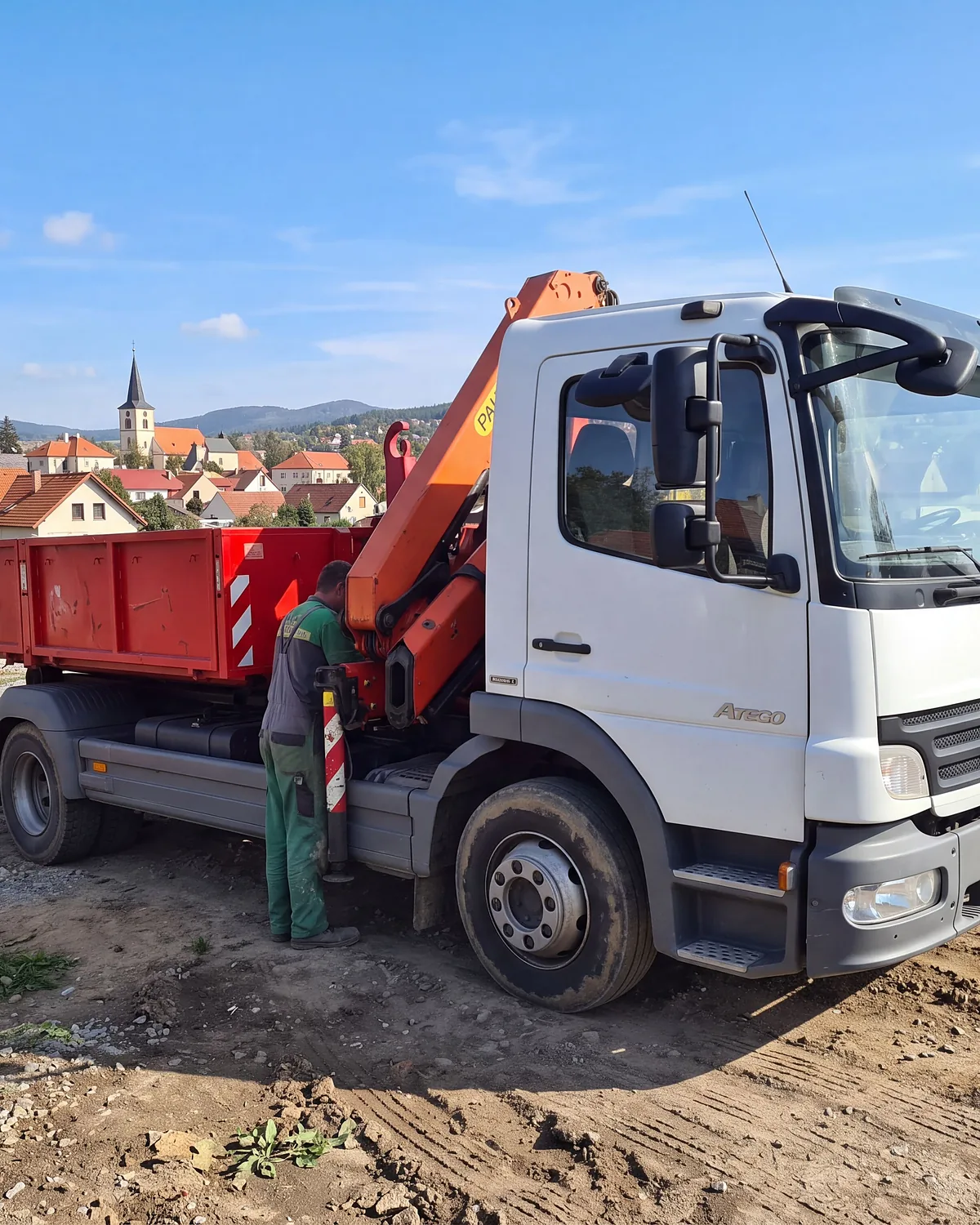 Pracovník u ovládání hydraulické ruky na staveništi